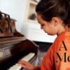 Title Image with a Girl in Orange Shirt Playing a Piano